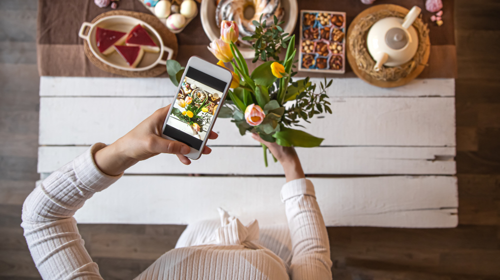 Social media post scheduling for gardening business using a smartphone surrounded by tools and plants.